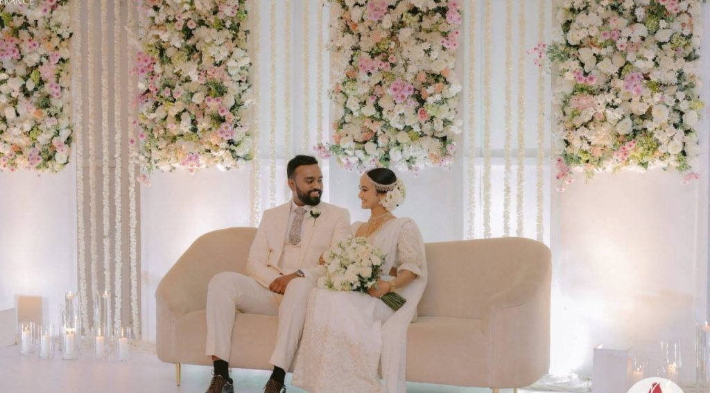 Couple on a blush settee under a floral wall